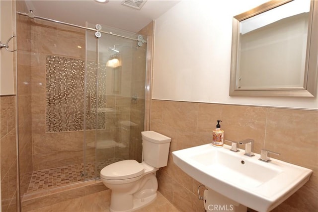 bathroom featuring walk in shower, tile patterned floors, toilet, sink, and tile walls