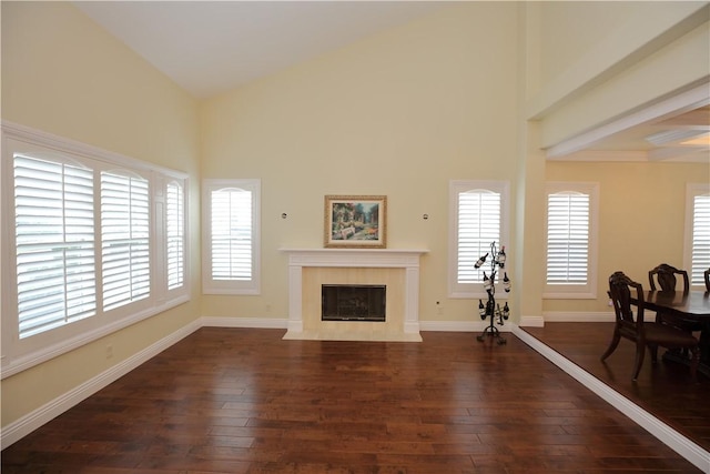 living room featuring a tiled fireplace, high vaulted ceiling, and dark hardwood / wood-style flooring