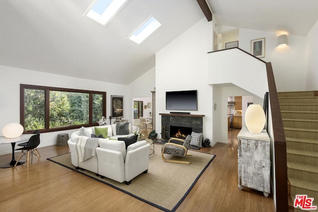 living room featuring beamed ceiling, hardwood / wood-style floors, high vaulted ceiling, and a skylight