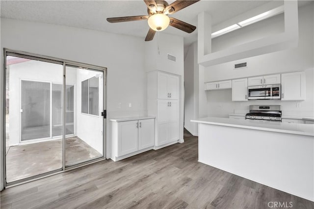 kitchen featuring white cabinetry, vaulted ceiling, light wood-type flooring, appliances with stainless steel finishes, and ceiling fan