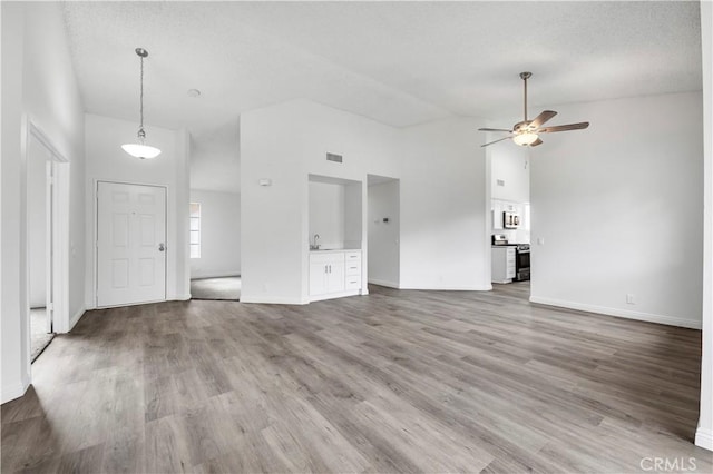 unfurnished living room with ceiling fan, sink, high vaulted ceiling, and light hardwood / wood-style flooring