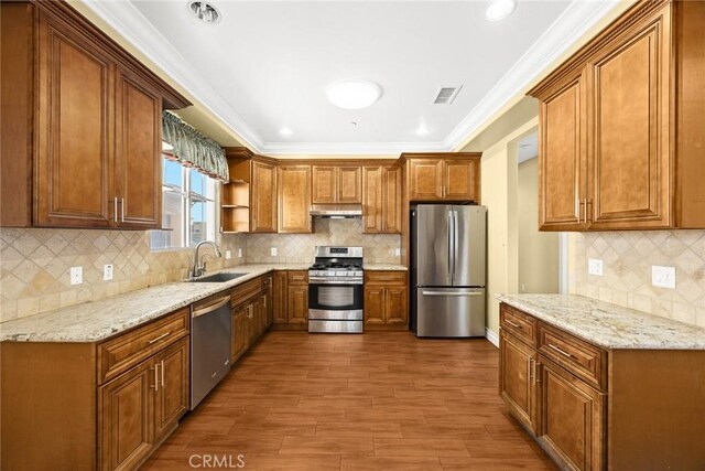 kitchen with sink, appliances with stainless steel finishes, ornamental molding, light stone countertops, and dark hardwood / wood-style flooring