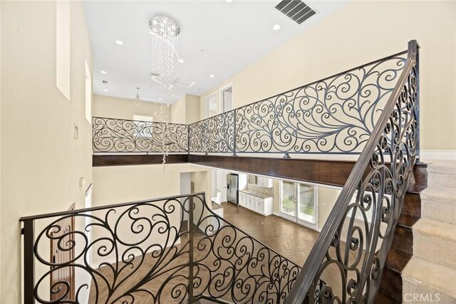 stairs featuring a high ceiling, parquet floors, and a notable chandelier