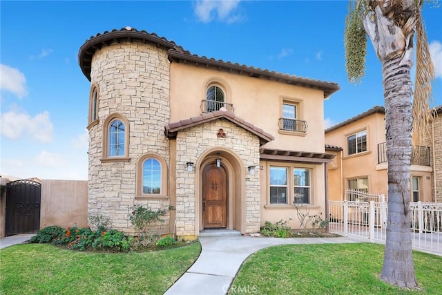 mediterranean / spanish house featuring a front lawn and a balcony