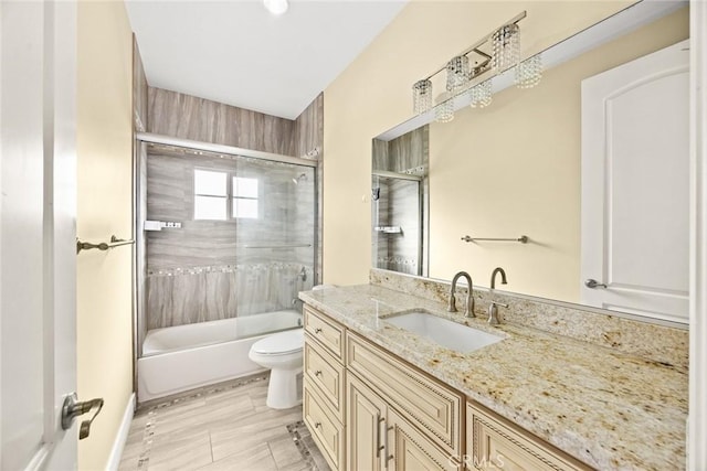 full bathroom with toilet, vanity, and bath / shower combo with glass door