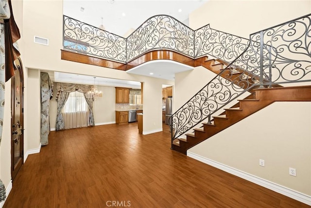 entryway with a notable chandelier, hardwood / wood-style flooring, and a high ceiling