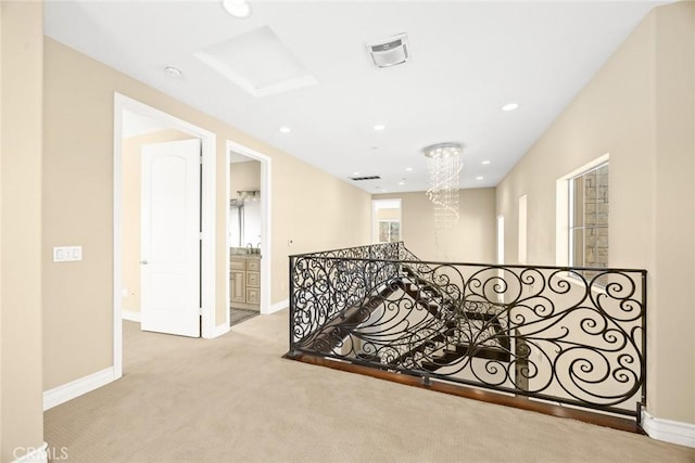 hallway featuring light carpet and a notable chandelier