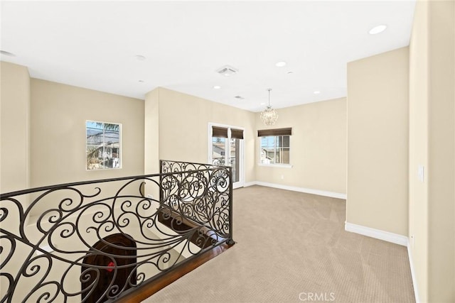 corridor featuring light colored carpet and an inviting chandelier