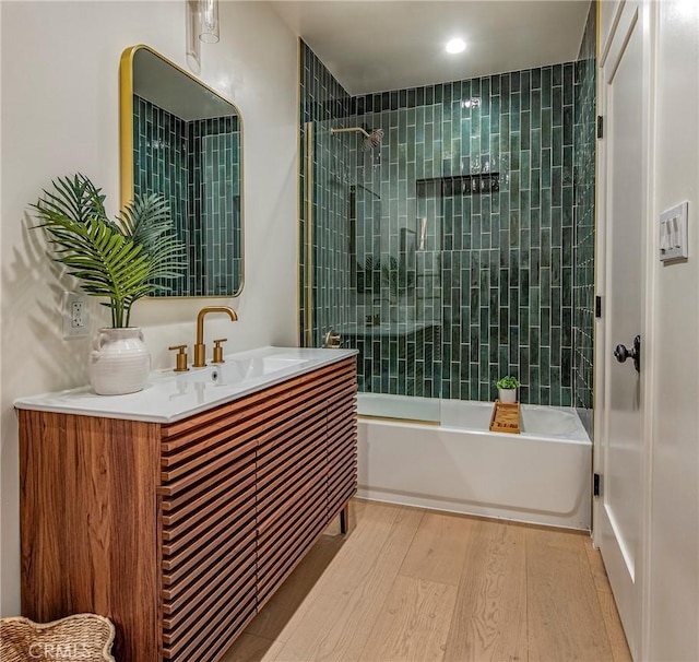 bathroom with vanity, tiled shower / bath combo, and wood-type flooring