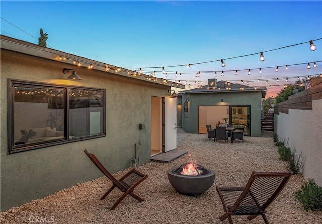 back house at dusk featuring a patio and a fire pit