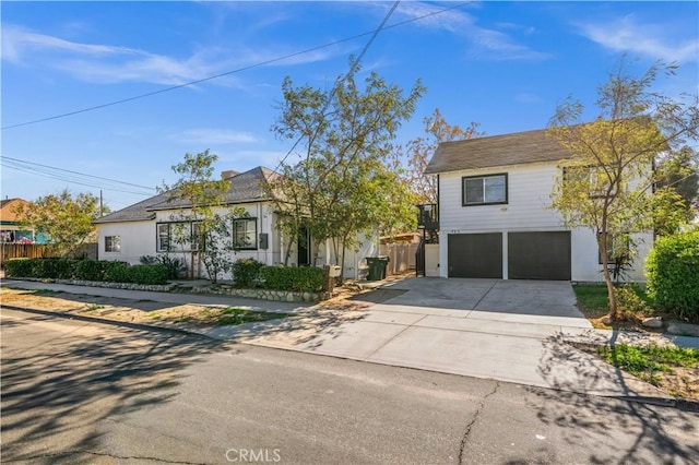 view of front facade featuring a garage, concrete driveway, and fence