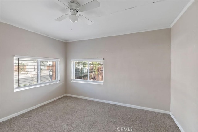 carpeted empty room with a ceiling fan, ornamental molding, and baseboards