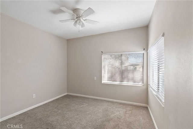 carpeted empty room with a ceiling fan and baseboards