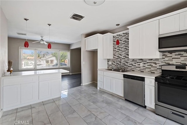 kitchen featuring stainless steel appliances, a sink, visible vents, light countertops, and tasteful backsplash