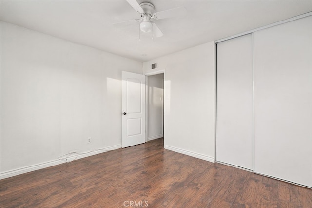 unfurnished bedroom with ceiling fan, dark hardwood / wood-style floors, and a closet