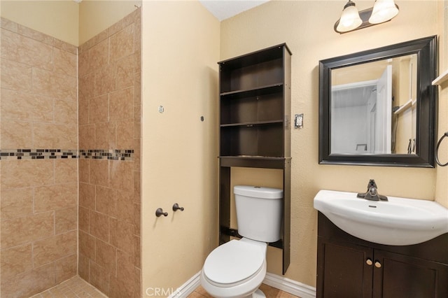 bathroom with tiled shower, vanity, and toilet