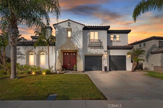 mediterranean / spanish home with a garage, a lawn, and a balcony