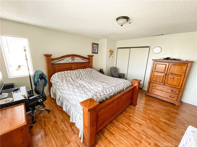 bedroom with light hardwood / wood-style flooring, a closet, and a textured ceiling