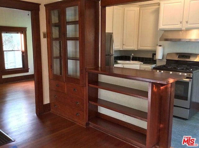 kitchen with wall chimney range hood, sink, appliances with stainless steel finishes, white cabinetry, and dark hardwood / wood-style flooring