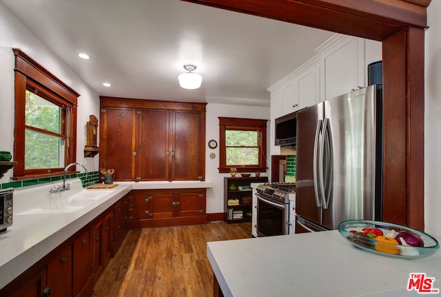 kitchen with white cabinetry, appliances with stainless steel finishes, sink, and light wood-type flooring