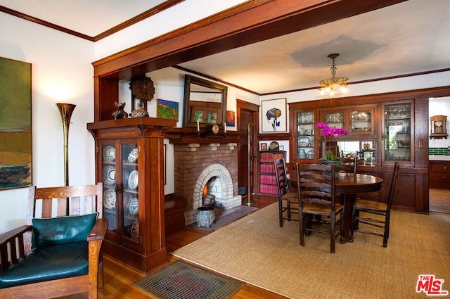 dining room with hardwood / wood-style floors, a notable chandelier, a fireplace, and ornamental molding