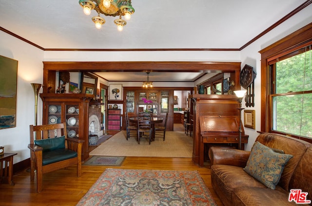 living room with wood-type flooring, ornamental molding, and a chandelier