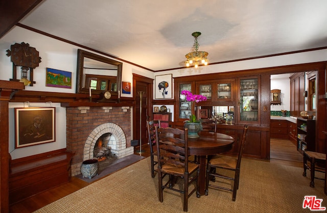 dining room with an inviting chandelier, ornamental molding, dark hardwood / wood-style floors, and a brick fireplace