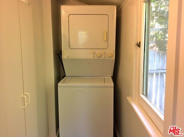 laundry area featuring stacked washer and clothes dryer and a healthy amount of sunlight