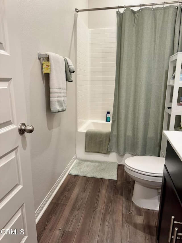 full bathroom with hardwood / wood-style flooring, shower / bath combo, vanity, and toilet