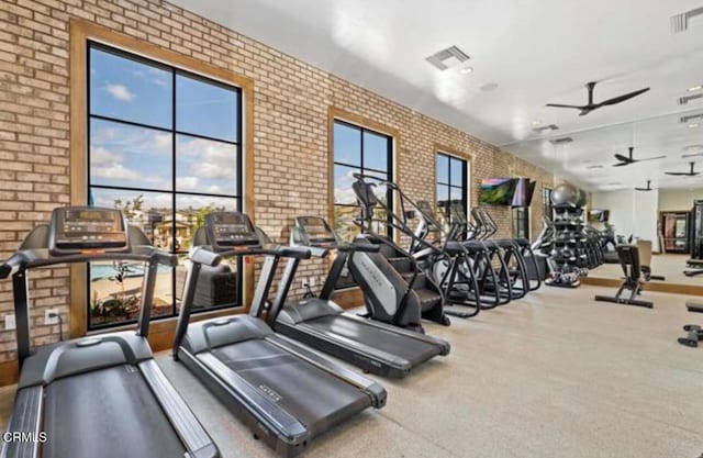 workout area with ceiling fan and brick wall