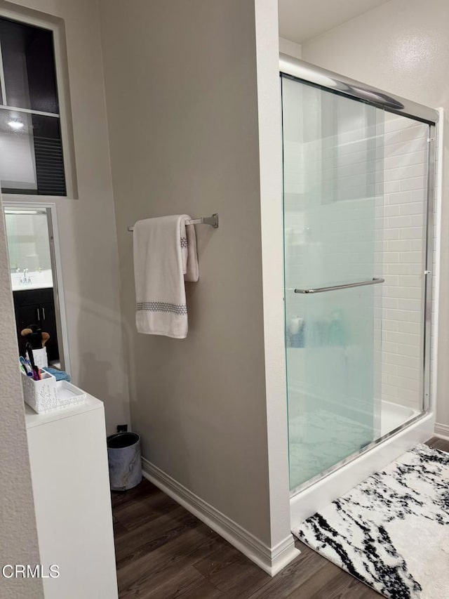 bathroom featuring an enclosed shower, washer / clothes dryer, and hardwood / wood-style flooring