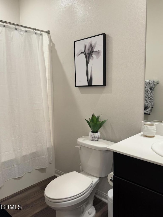 full bathroom with hardwood / wood-style flooring, shower / bath combo, vanity, and toilet