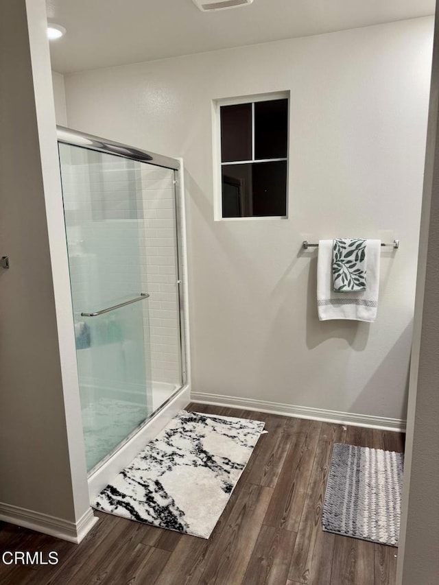 bathroom with an enclosed shower and hardwood / wood-style floors