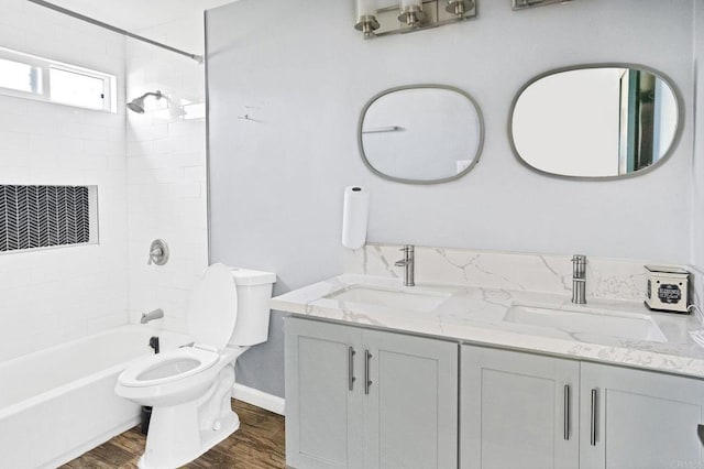 full bathroom featuring vanity, tiled shower / bath, hardwood / wood-style flooring, and toilet