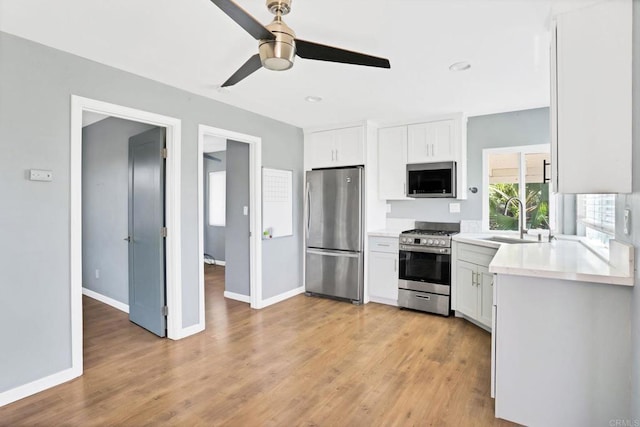 kitchen featuring white cabinetry, appliances with stainless steel finishes, sink, and light hardwood / wood-style flooring