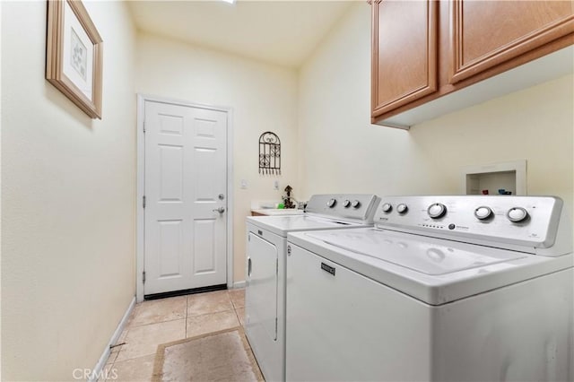 clothes washing area featuring washing machine and dryer, cabinets, and light tile patterned flooring