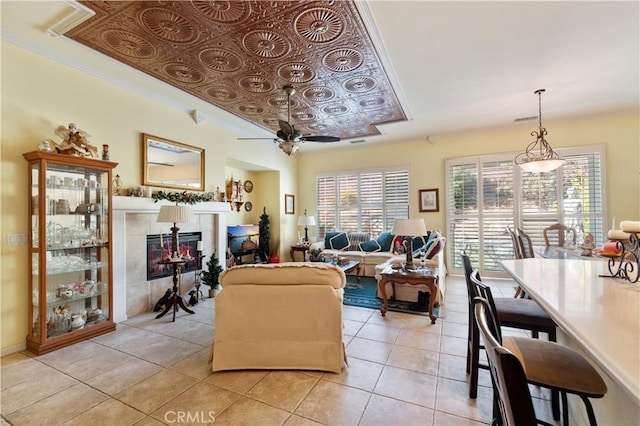 living room featuring ceiling fan, a tile fireplace, a healthy amount of sunlight, and light tile patterned flooring