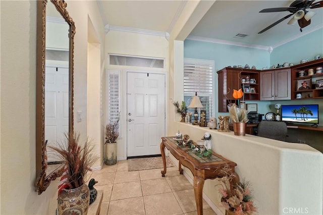 tiled entryway with ceiling fan, ornamental molding, and built in desk