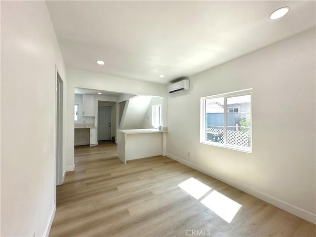 empty room with a wall mounted AC and light wood-type flooring