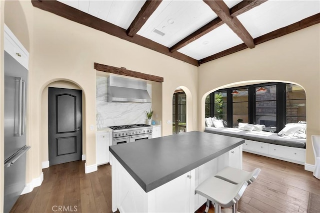 interior space with decorative backsplash, beamed ceiling, wall chimney exhaust hood, and white cabinets