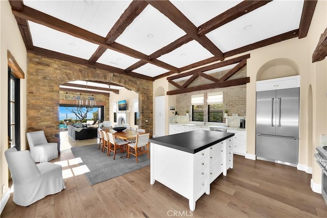 kitchen featuring built in fridge, hardwood / wood-style floors, white cabinetry, a center island, and beam ceiling