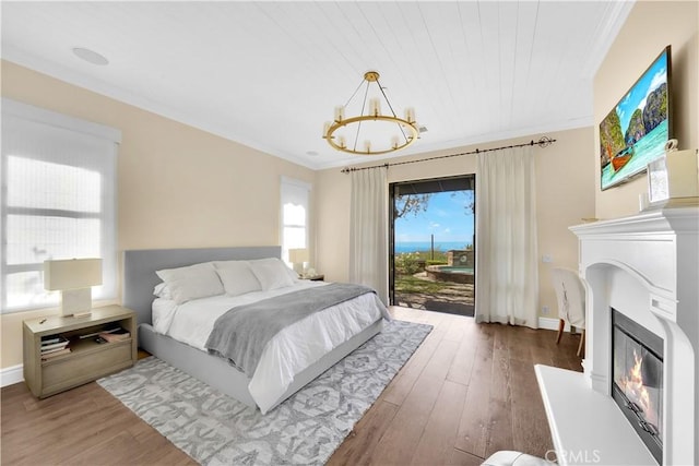 bedroom featuring wood ceiling, dark hardwood / wood-style floors, a notable chandelier, ornamental molding, and access to outside