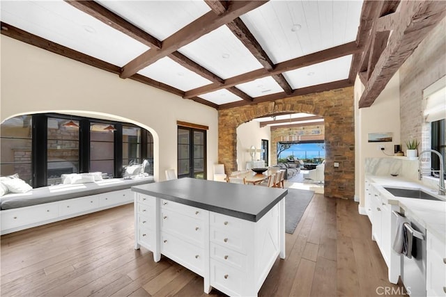 kitchen with beamed ceiling, dark wood-type flooring, sink, and white cabinets