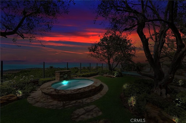 pool at dusk featuring an in ground hot tub