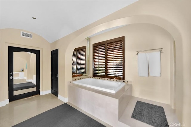 bathroom with lofted ceiling and tiled tub