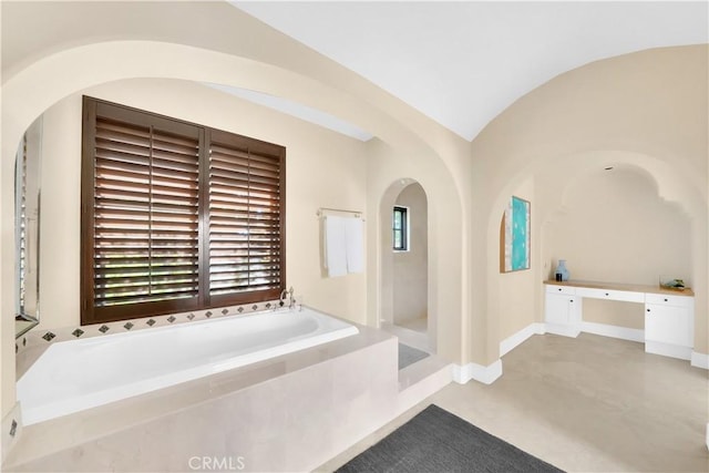 bathroom featuring vaulted ceiling and a tub