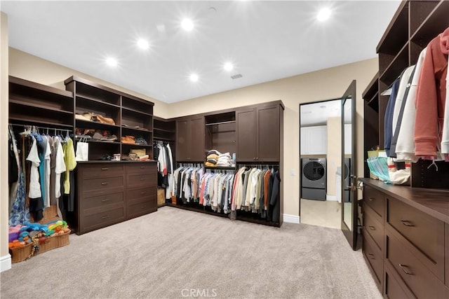 walk in closet featuring light colored carpet and washer / dryer