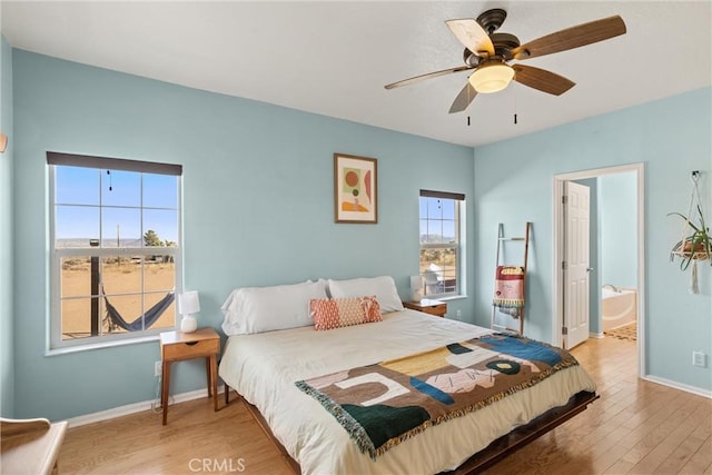 bedroom with multiple windows, hardwood / wood-style floors, connected bathroom, and ceiling fan