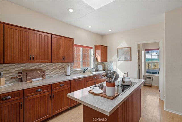 kitchen featuring decorative backsplash, stovetop, a kitchen island, and light wood-type flooring