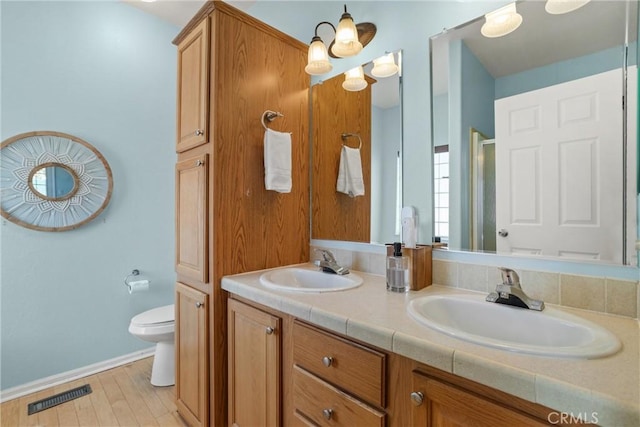 bathroom with a shower with door, vanity, and toilet